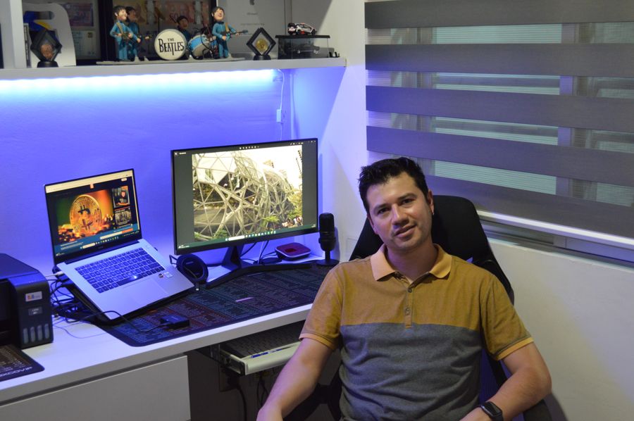 Jorge Padilla sentado en su escritorio, con una laptop, un monitor y luz LED azul de fondo
